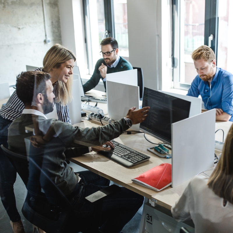 A group of IT professionals working collaboratively at their desks, each focused on their computers, in a modern office environment. Their teamwork emphasises the delivery of Managed IT Services and innovative technology solutions.